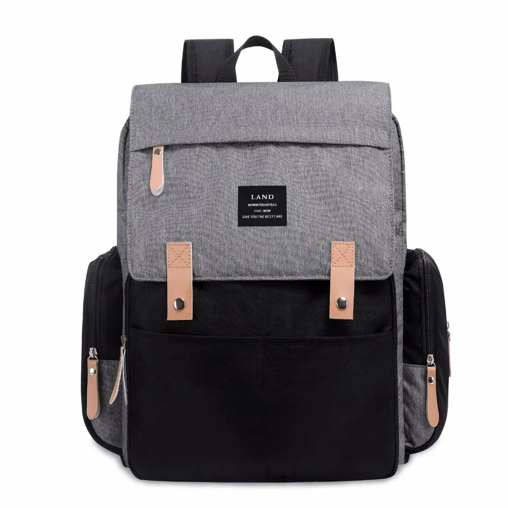LAND Mommy large grey diaper backpack with changing mat, shown with baby care items.