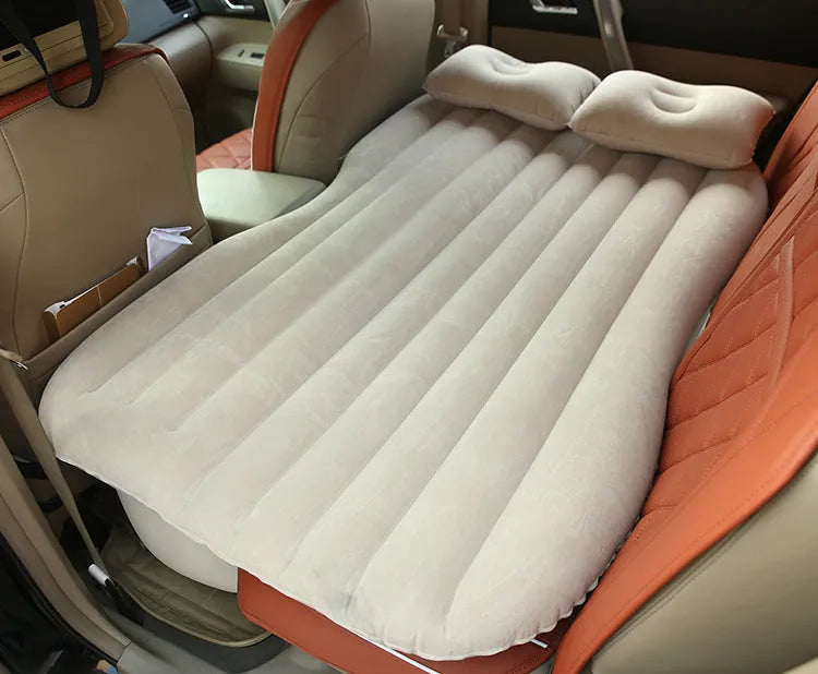 Black inflatable car bed with flocking surface and two pillows, shown folded next to a storage bag.