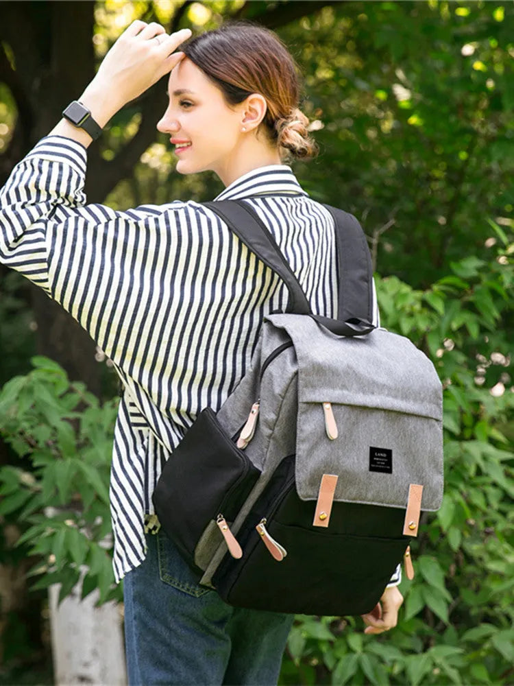 LAND Mommy large grey diaper backpack with changing mat, shown with baby care items.