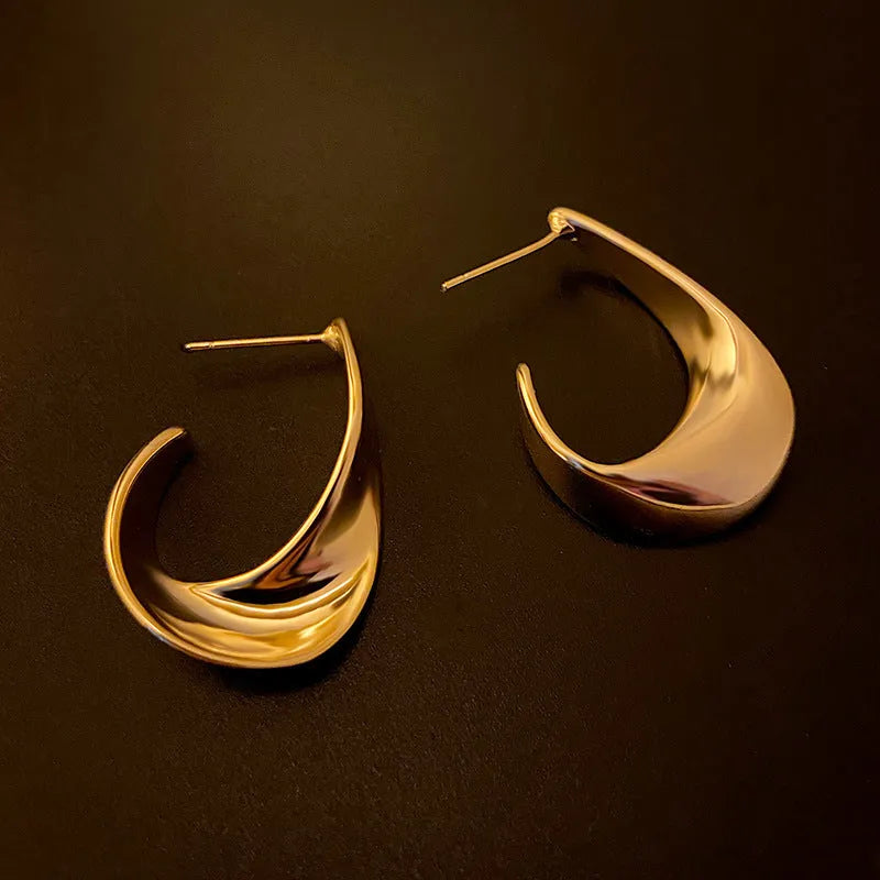 Twisted geometric metal earrings with electroplated gold finish and round design elements