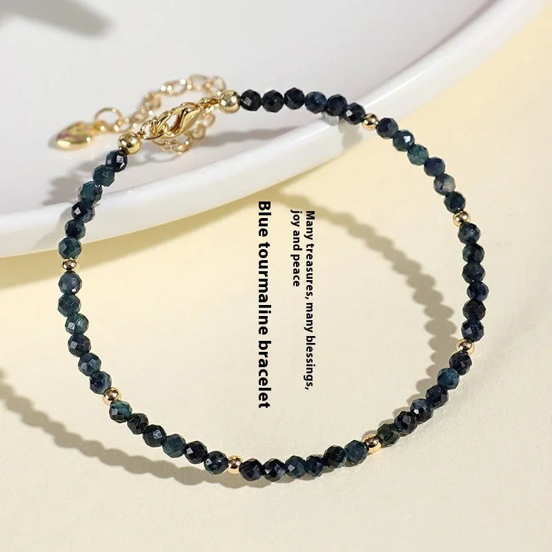 Close-up of a women's blue tourmaline bracelet with 3mm beads and gold spacer beads.