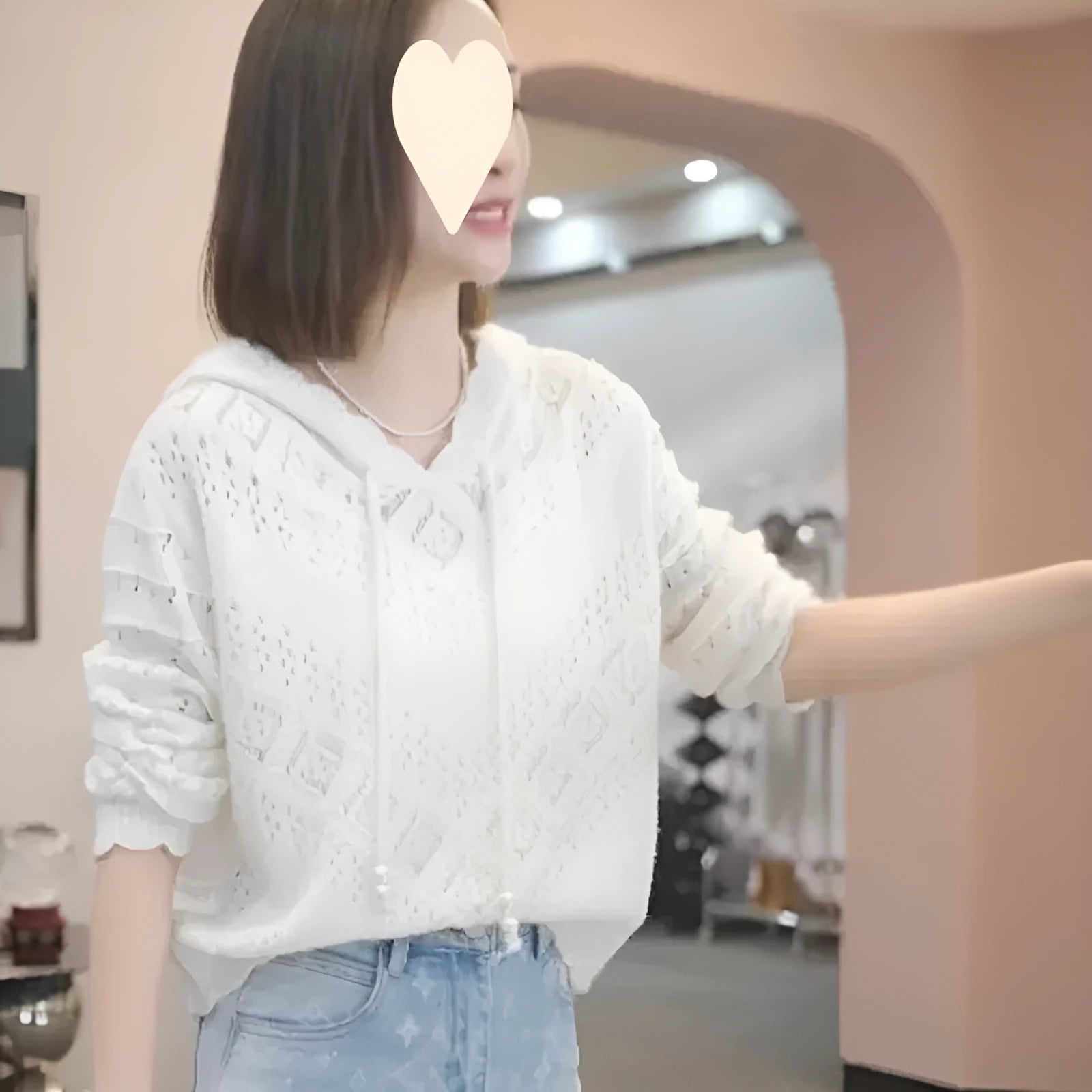 Woman wearing a light blue, hooded crochet longsuit undershirt with a hollow knit pattern and long sleeves.