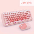 Candy pink wireless keyboard and mouse set on a desk next to a notebook computer.