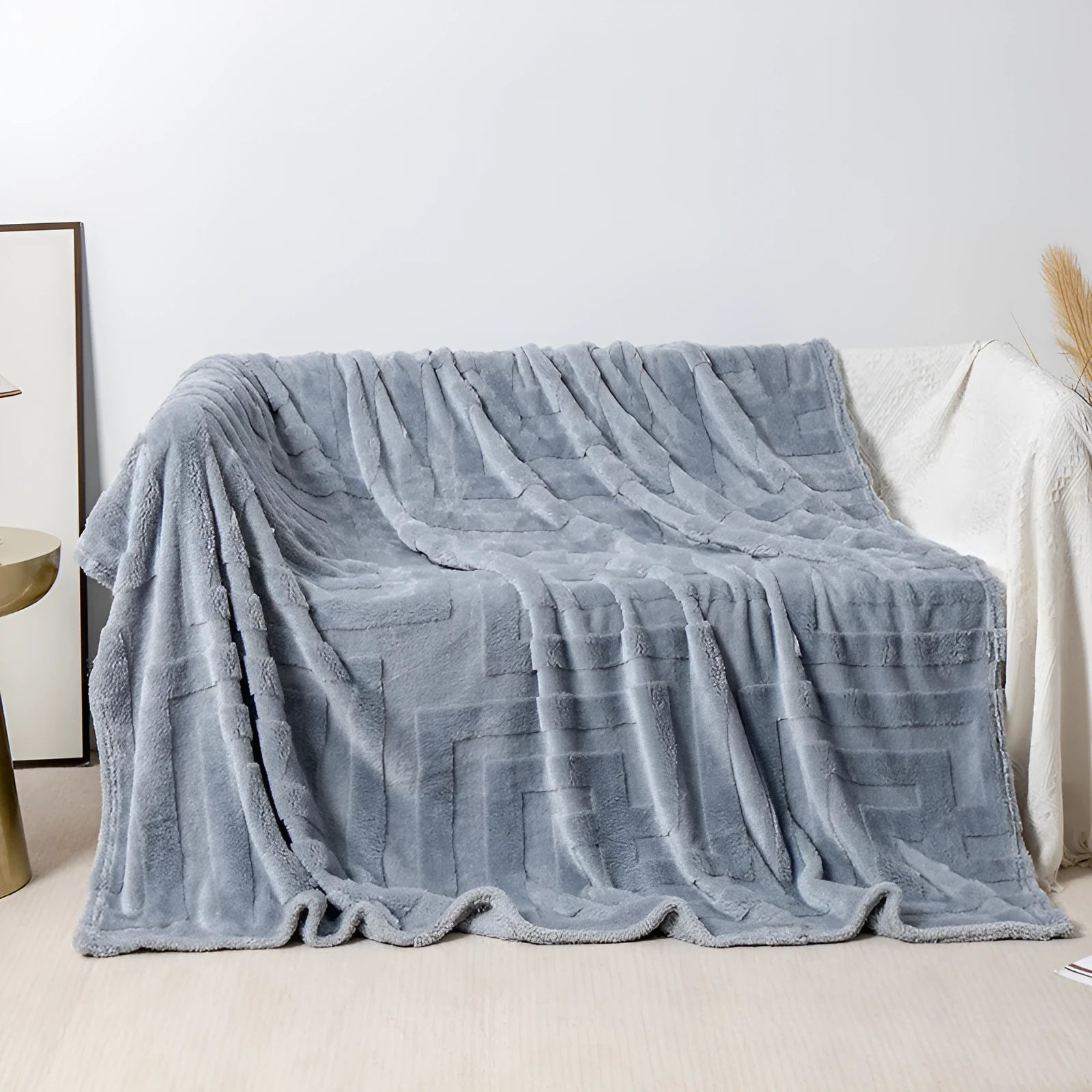 Thick coral fleece sofa blanket in a choice of colours and sizes draped over a grey sofa
