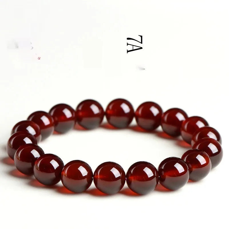 Natural orange red garnet crystal bead bracelet with a ruyi charm on a wrist.