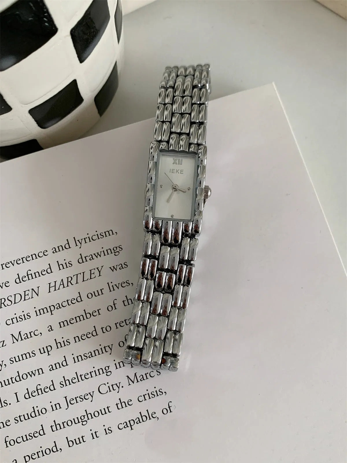 Women's bracelet-style watch with 15mm dial, silver stripe strap, and butterfly clasp