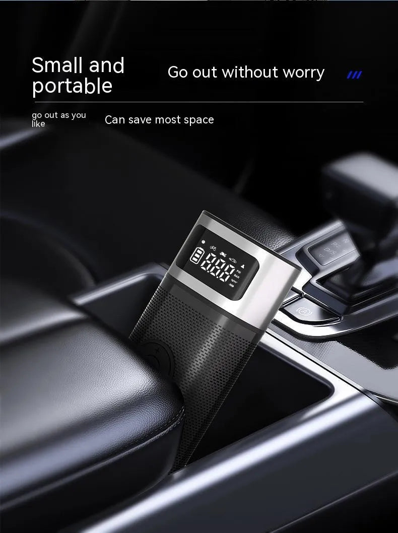 Black portable wireless smart air pump with display, charging cable and nozzle attachments on a dark surface.
