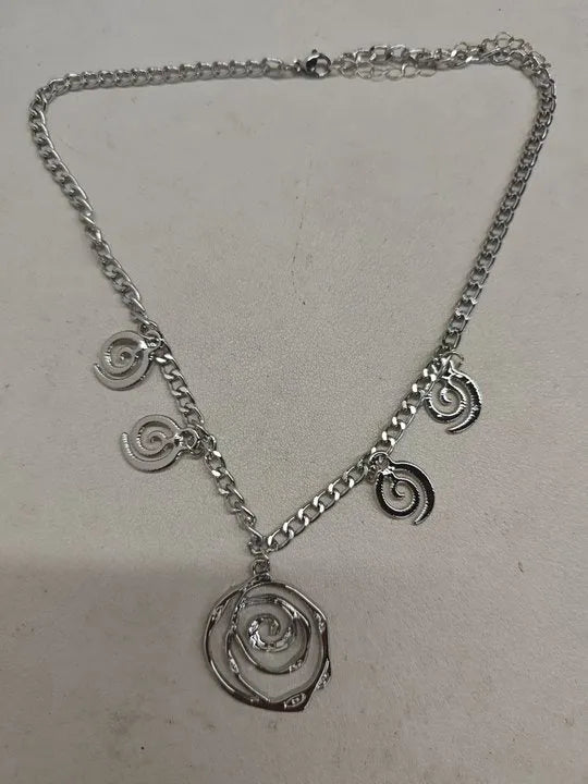 Gold spiral donut design necklace, bracelet, and earrings set on a grey background.
