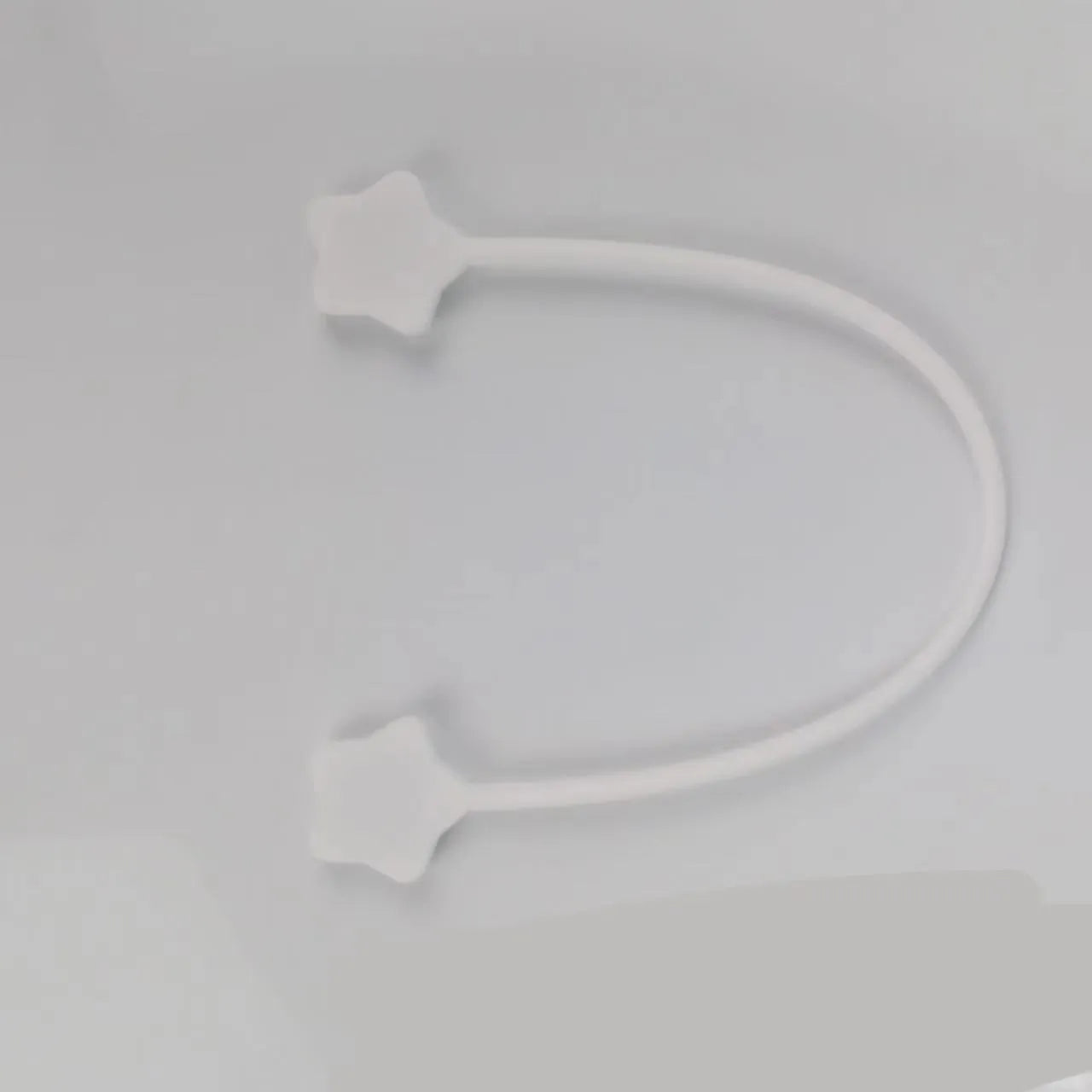 Purple silicone star-shaped magnet winder for clipping onto and organising headphone or phone charging cables.