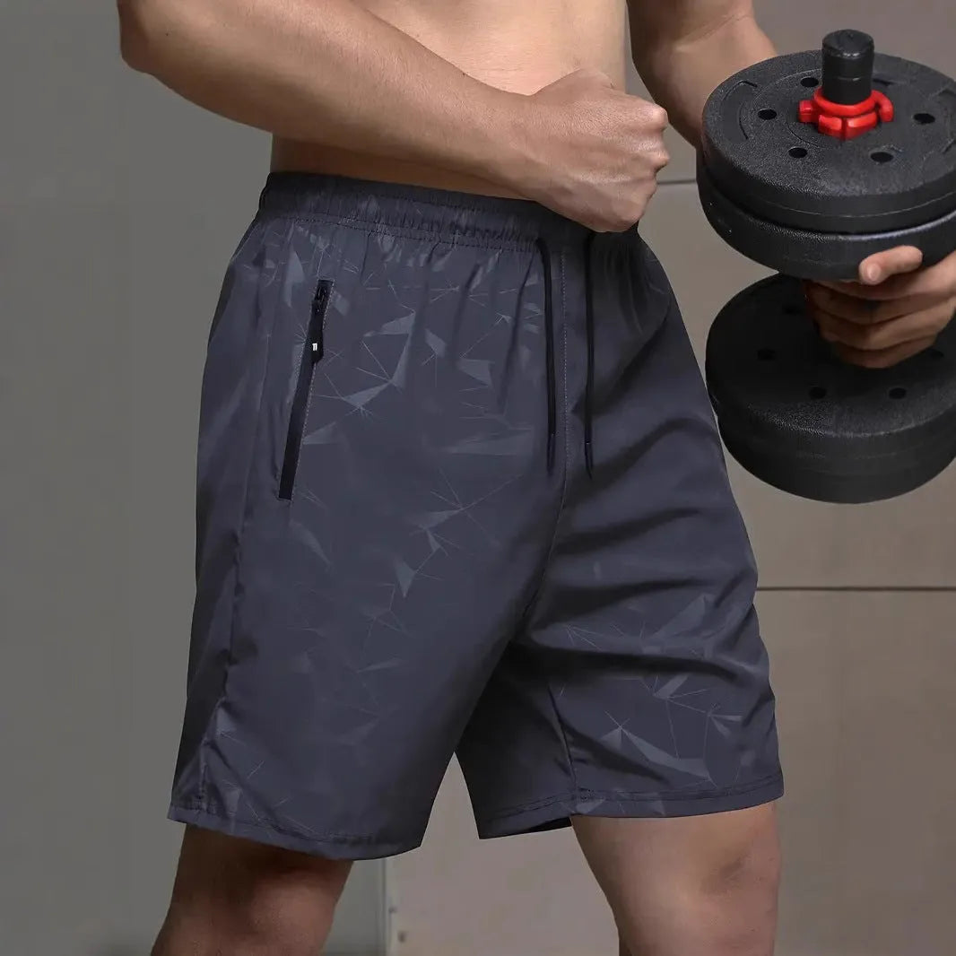 Man wearing loose grey polyester sports shorts on a beach.