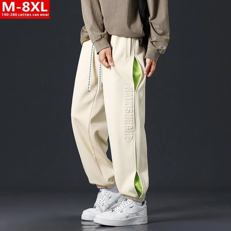 Man wearing loose grey-green cotton trousers with banded ankles and stitching detail.