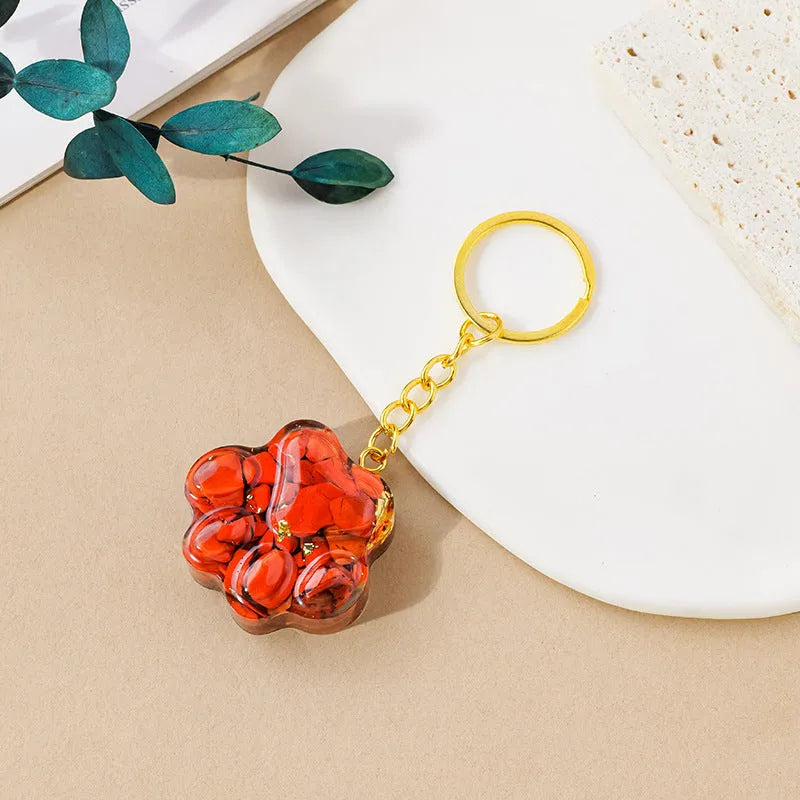 Natural crystal cat's paw shaped keychain charm on a keyring, showing colour variations of different gemstones.