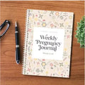 A5 sized weekly pregnancy diary notebook open on a page with the Pregnancy Weekly format