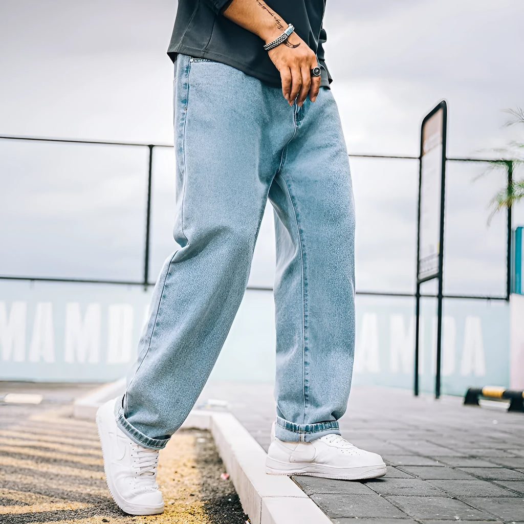 Man wearing loose straight-leg casual jeans in dark blue cotton fabric.
