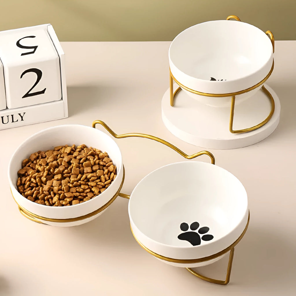 White ceramic cat bowl with decorative pattern sitting in a black iron frame stand.