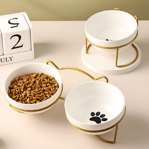 White ceramic cat bowl with decorative pattern sitting in a black iron frame stand.