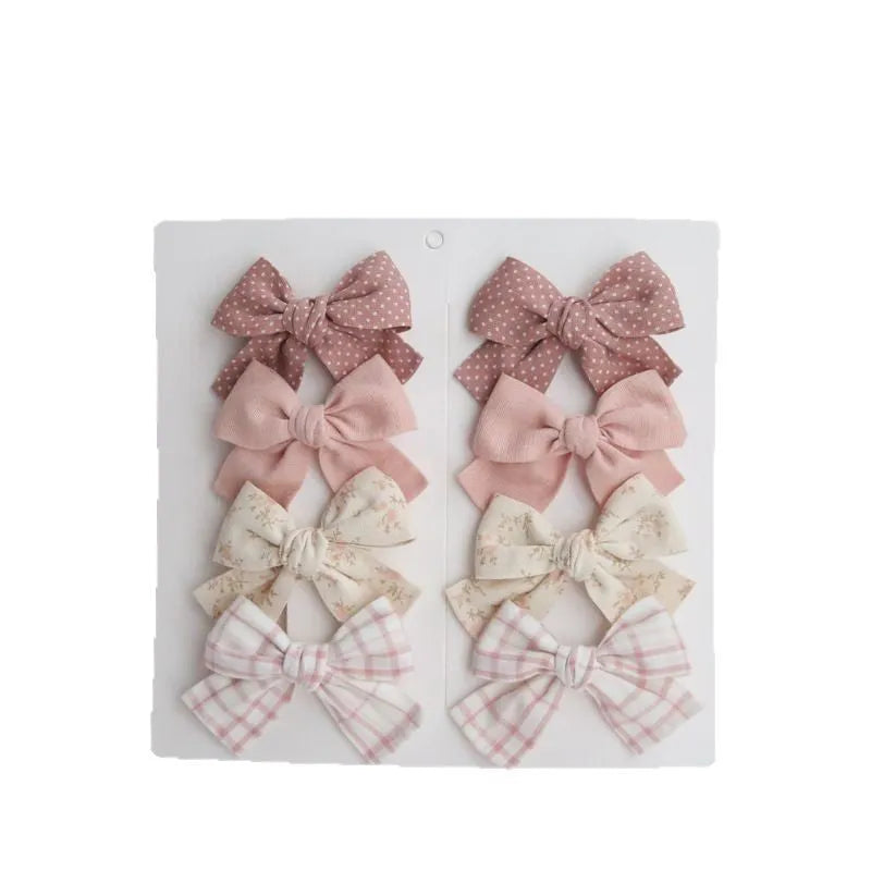 Set of eight fabric hairclips with dovetail bows in a chosen colour like beige grid dots or pink.