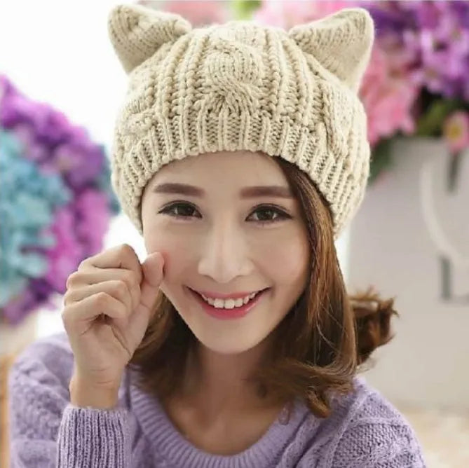 Handmade red knitted beanie with 3D cat ears on a white background.