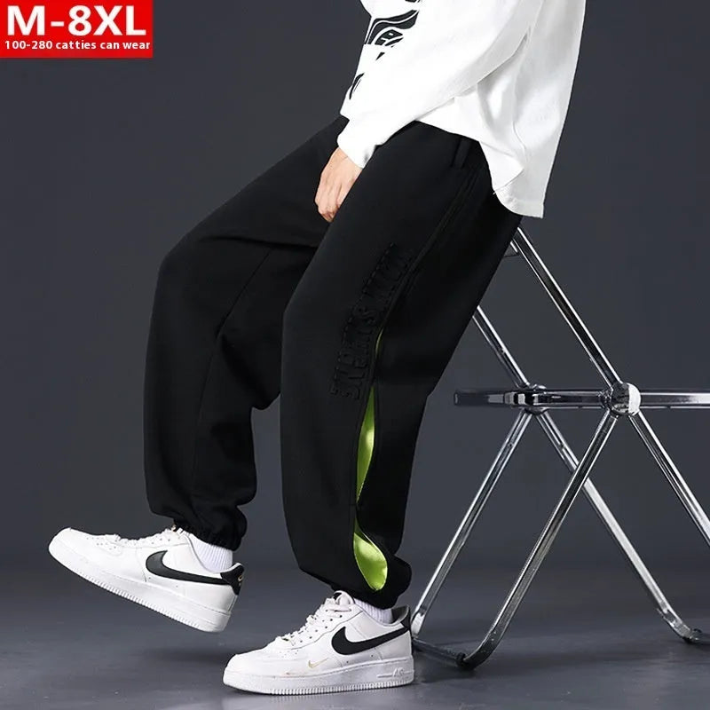 Man wearing loose grey-green cotton trousers with banded ankles and stitching detail.