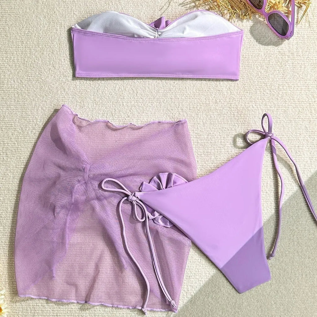 Women's pink tube top bikini with large 3D flower, matching bottoms, and skirt laid flat.