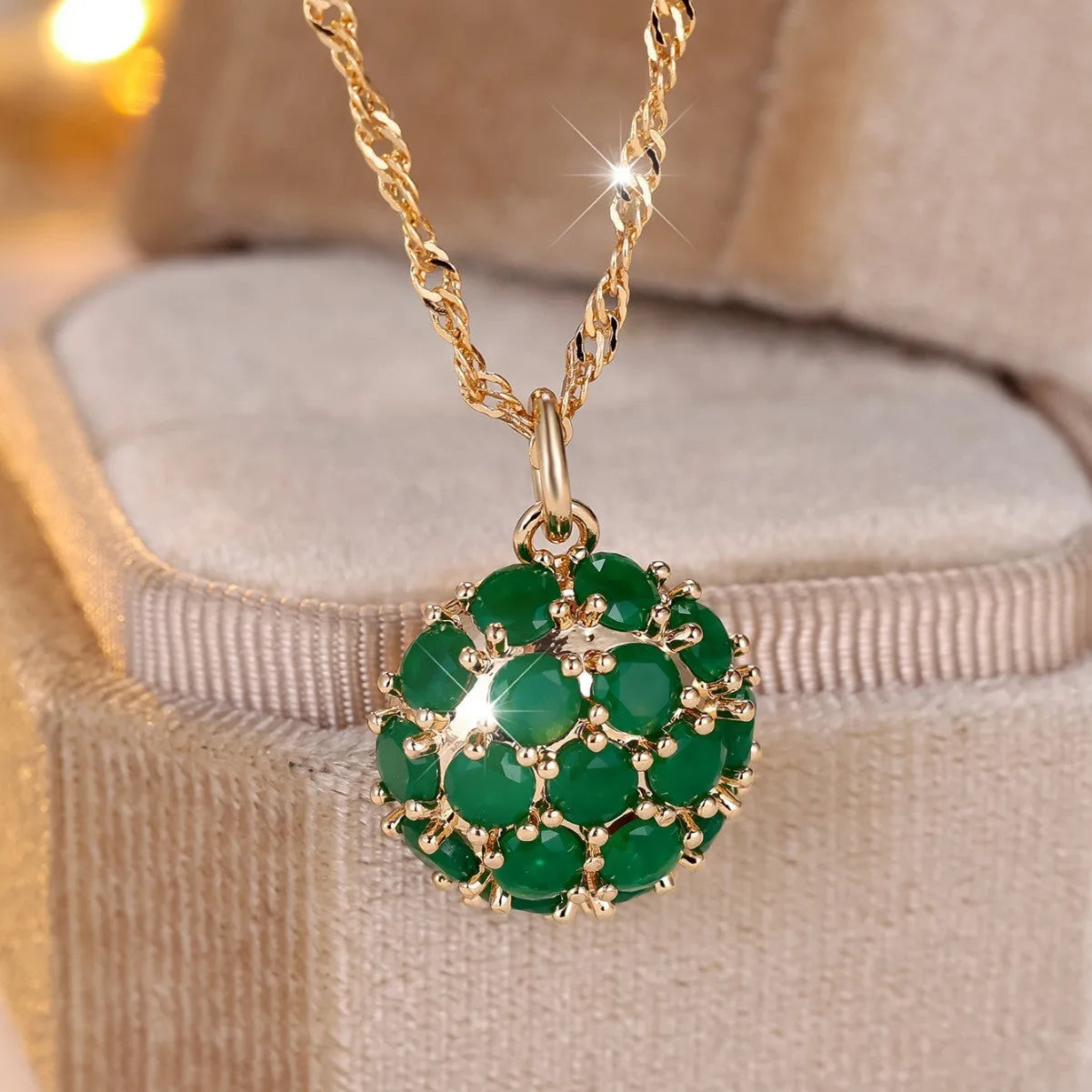 Champagne gold geometric pendant necklace with a round emerald stone and diamond accents on an adjustable chain.