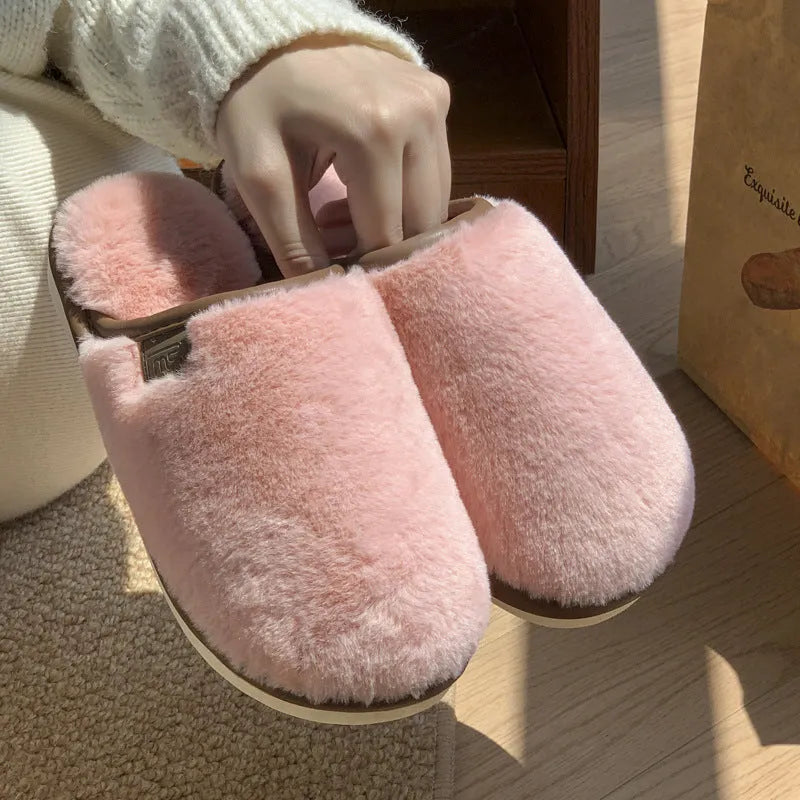 A pair of solid colour plush winter slippers with a non-slip PVC sole and car stitching detail.