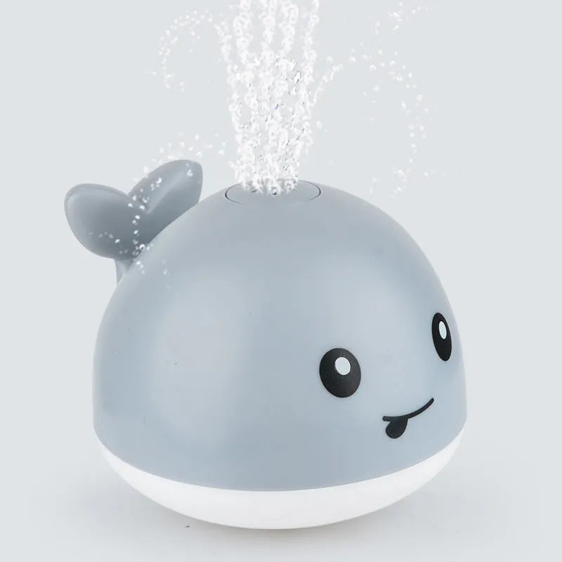 Electric whale-shaped baby bath toy with water spray, LED lights, and automatic water sensor