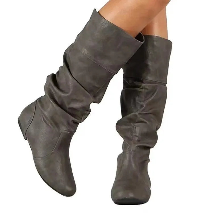 Women's flat slip-on long boots with round toe in black, shown on a foot.