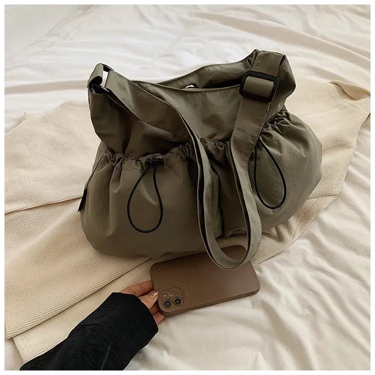 Soft green pleated foldable crossbody bag showing split pocket and internal mobile phone compartment