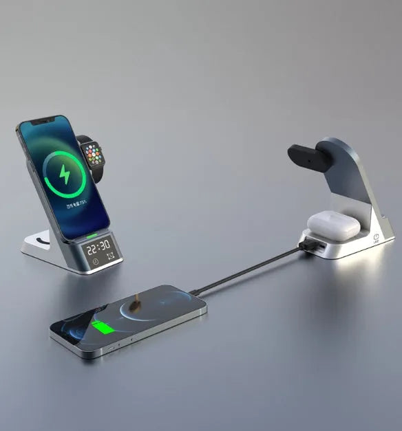 Black six-in-one wireless charging alarm clock station on a desk next to a phone and smartwatch.