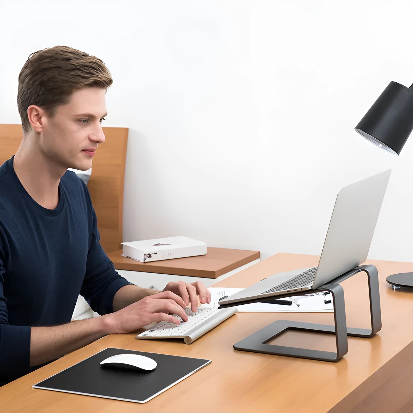 Black aluminium alloy laptop stand on a desk, elevating a silver laptop.