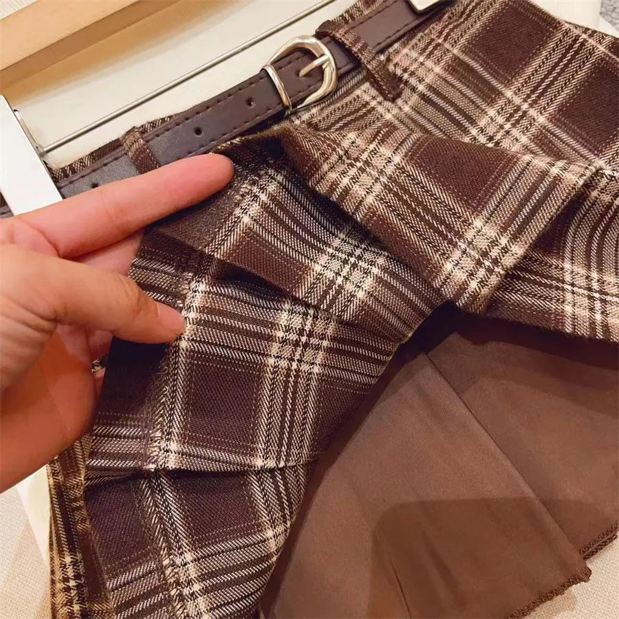 A girls' plaid pleated skirt in an A-line style, shown in a casual setting.