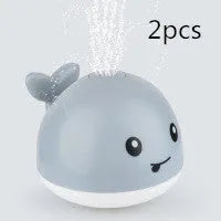 Electric whale-shaped baby bath toy with water spray, LED lights, and automatic water sensor