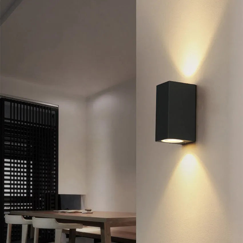 Satin black aluminium and glass LED wall lamp mounted on an interior wall.