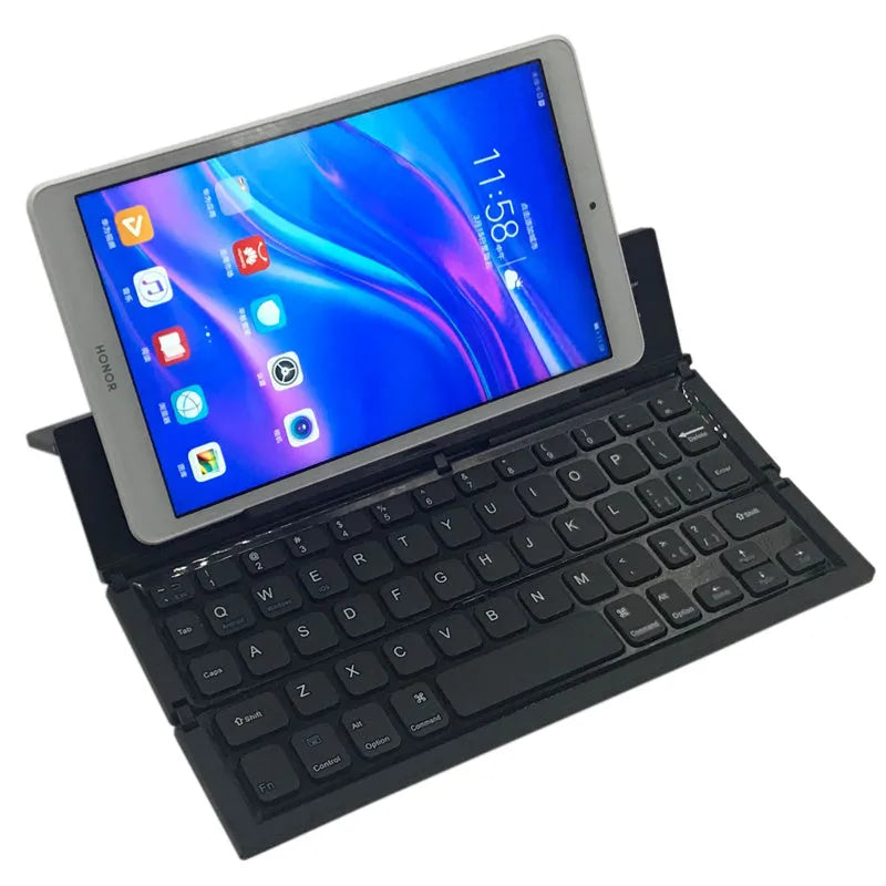 A black mini folding wireless Bluetooth keyboard shown open next to a tablet.