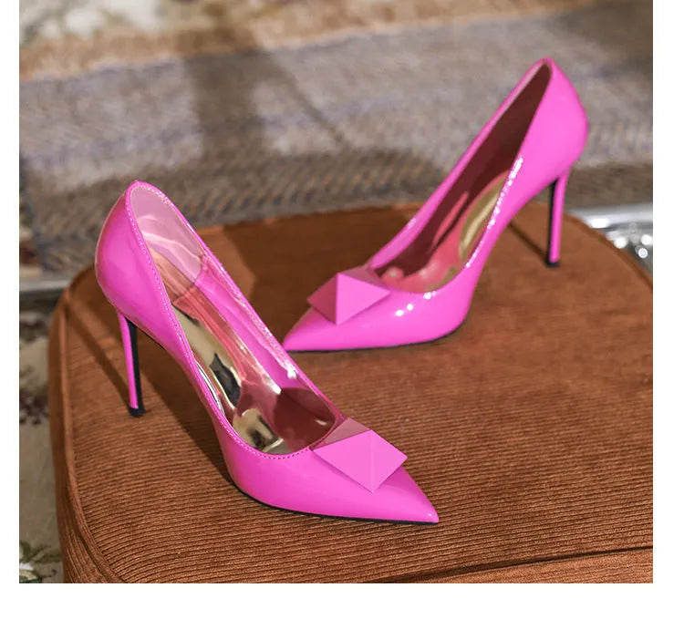 Pink patent leather women's stiletto heels with pointed toe and ankle buckle.