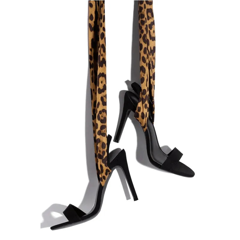 Light brown leopard print women's high heel sandals with cross-straps and a tall fine heel on a rubber sole.