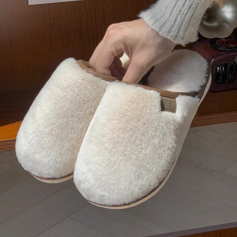 A pair of solid colour plush winter slippers with a non-slip PVC sole and car stitching detail.