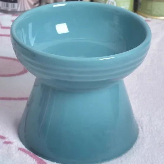 Black ceramic pet bowl with a chin-high foot and raised neck protector on a white background.