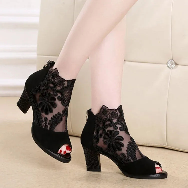 Black women's gladiator sandals with floral lace upper, high square heel, and a front zip closure.