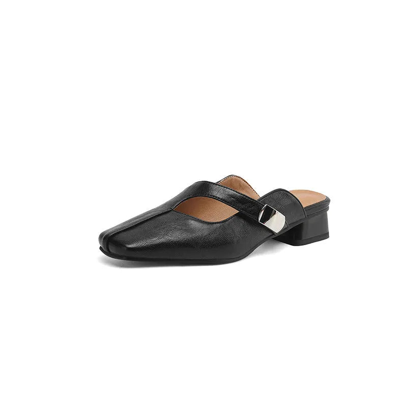 A pair of beige square head low heel slippers with a rubber sole on a wooden deck.