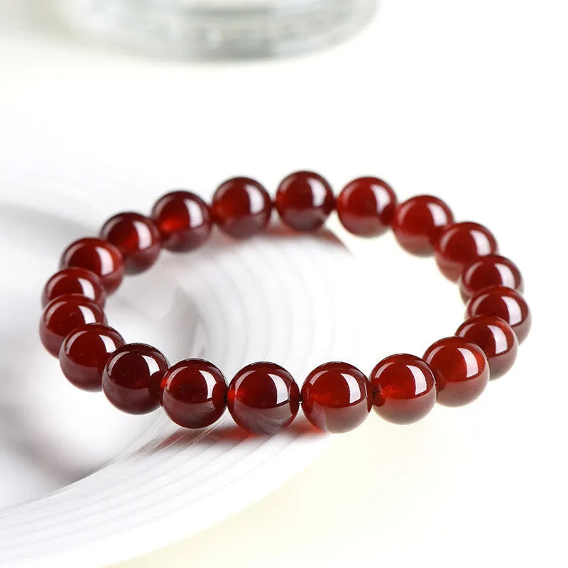 Natural orange red garnet crystal bead bracelet with a ruyi charm on a wrist.