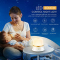 White cylindrical bedside night light with touch controls and motion sensor on a table.