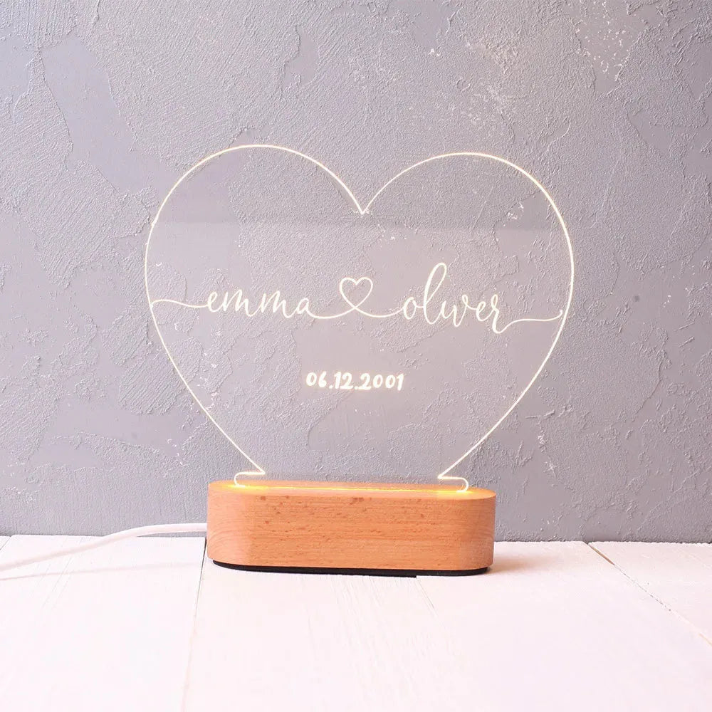 Custom transparent acrylic night light with engraved names and date, lit by LED base.