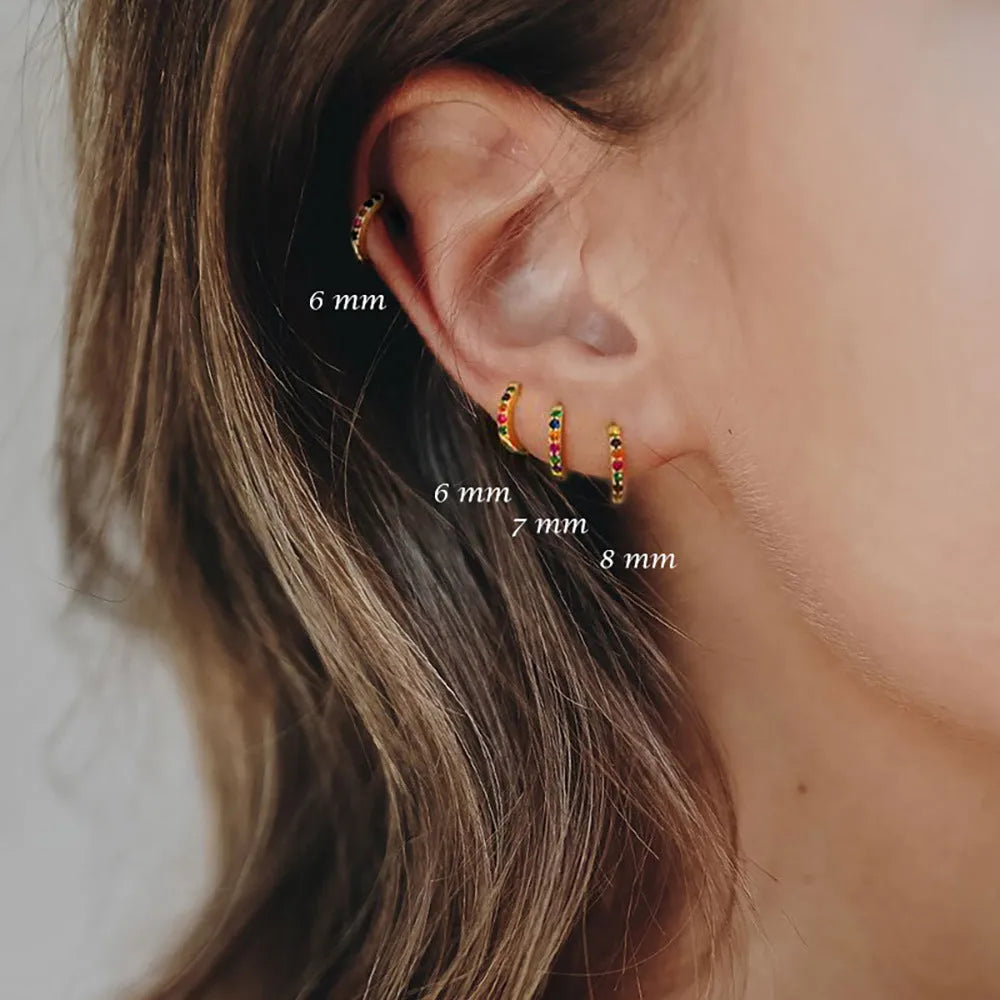 Circle zircon perforated stud earrings in gold, rose gold, and silver colour on a white background.
