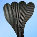 A pair of thin, black 3K carbon fibre running insoles showing the textured weave pattern, placed next to a running shoe.