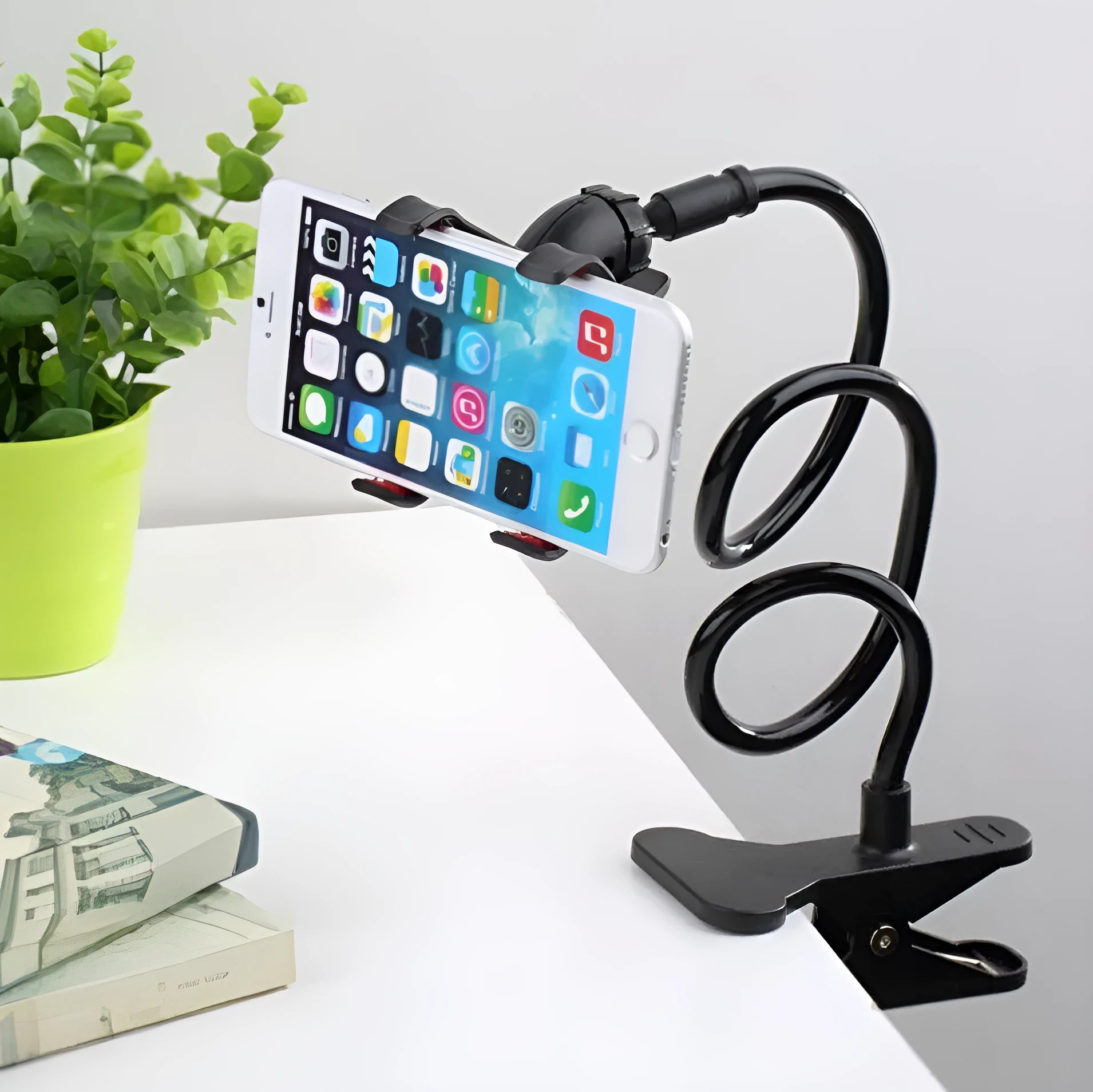 Black portable mobile phone holder with a long flexible arm and a V-clip, extended on a surface.