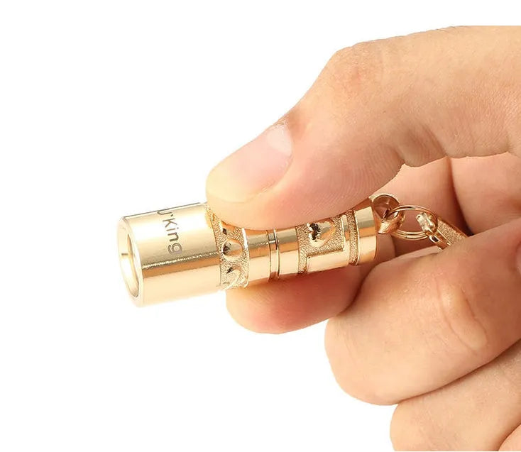 Gold-coloured zinc alloy waterproof mini LED flashlight on a keychain.