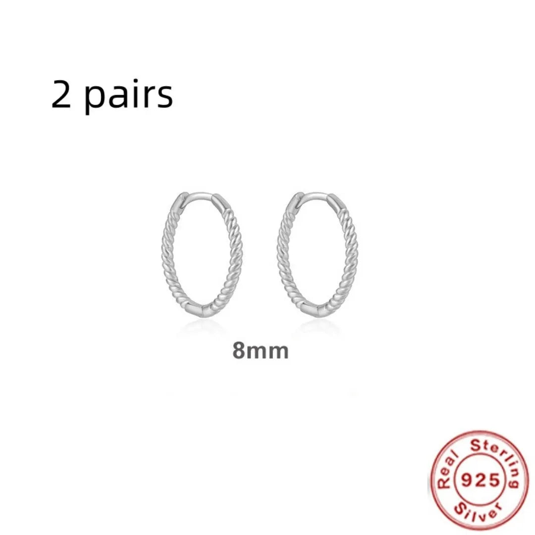 A pair of twisted sterling silver round earrings in a geometric design on a white background.