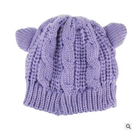 Handmade red knitted beanie with 3D cat ears on a white background.